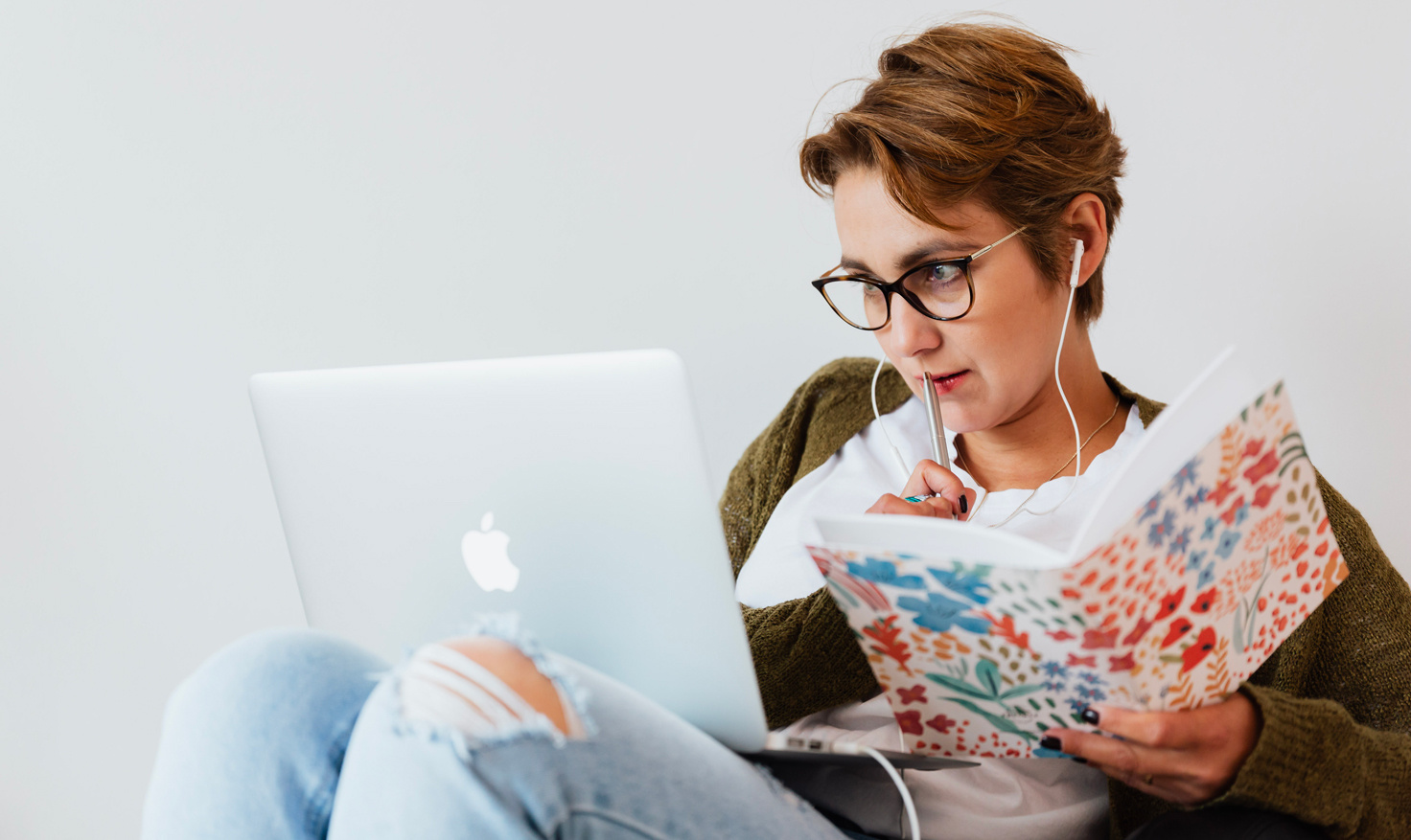 Une femme regarde son ordinateur avec intérêt. Elle tient un cahier et un crayon dans ses mains et est prête à prendre des notes. - Article de blog Eventdrive