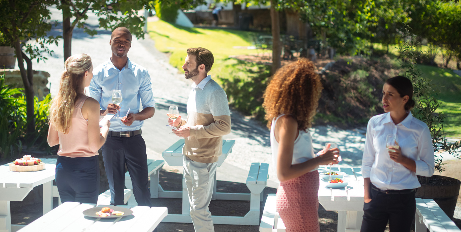 Un groupe de personnes discute et profite d'une boisson lors d'un événement en plein air dans un cadre verdoyant. - Article de blog Eventdrive