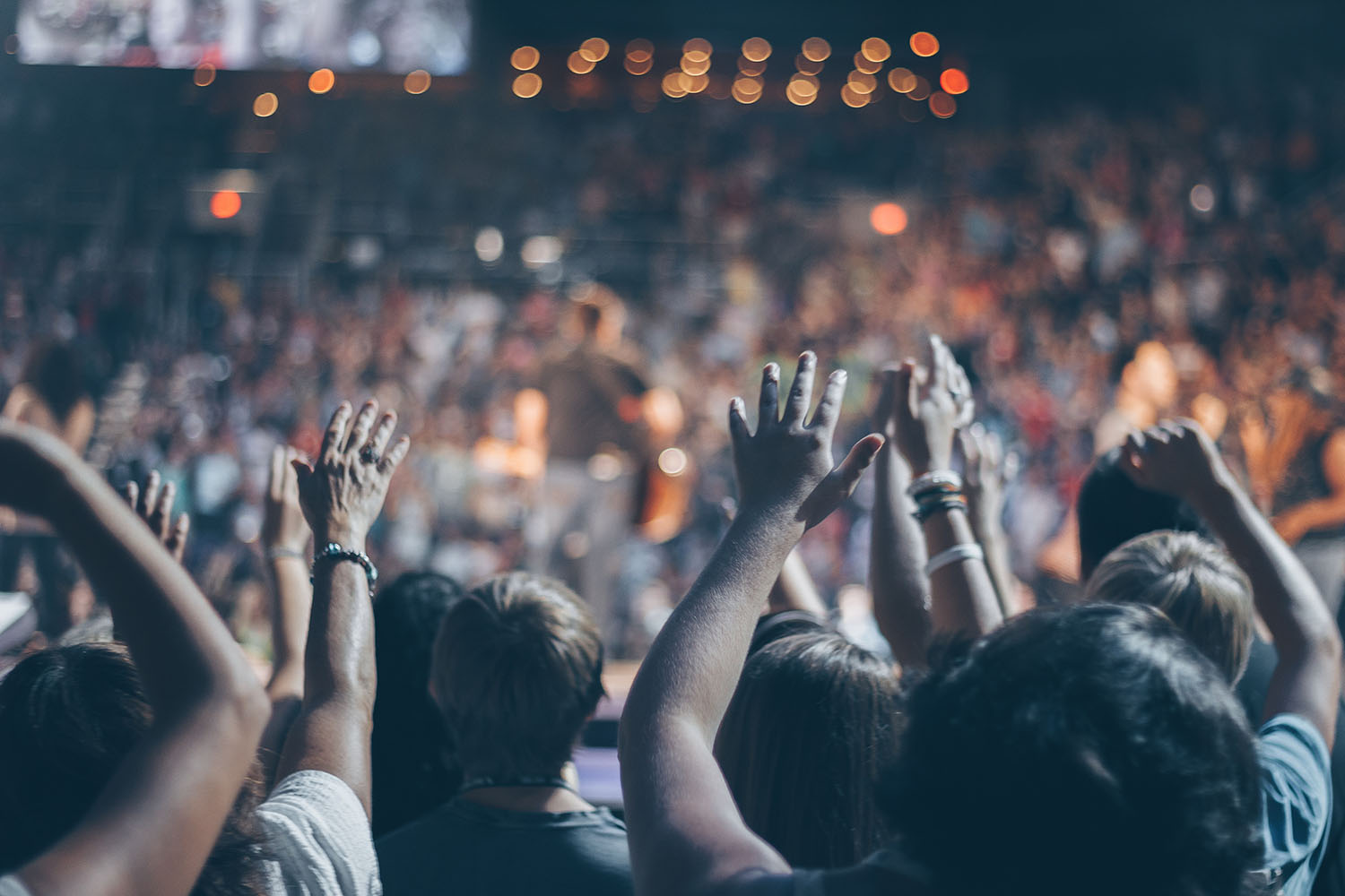 A crowd of people at an event, arms raised toward the stage. - Eventdrive Blog Article