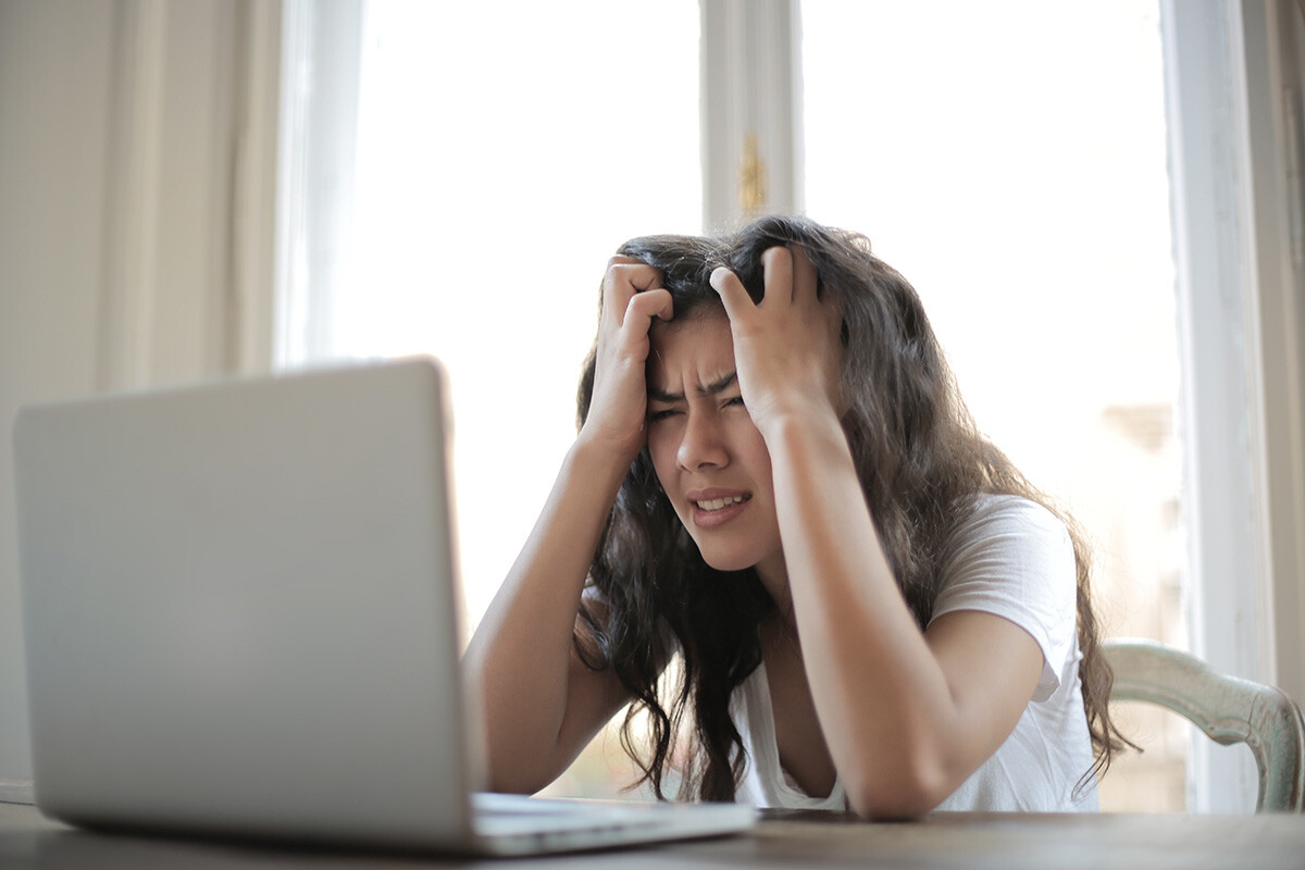 Une femme, l'air exaspéré, se tient la tête devant un ordinateur portable. - Article de blog Eventdrive