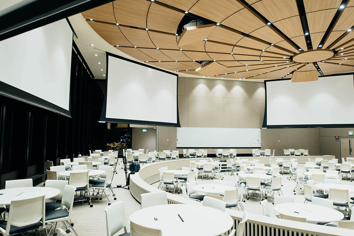 Une grande salle de réception équipée de grands écrans, de tables rondes et de nombreuses chaises, idéale pour événements professionnels et conférences. - Article de blog Eventdrive