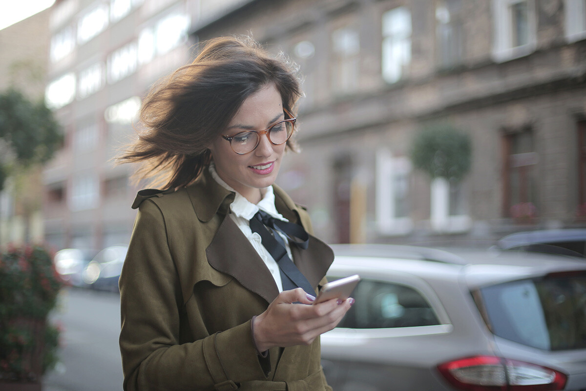 Une femme sourit en regardant son téléphone portable - Article de blog Eventdrive