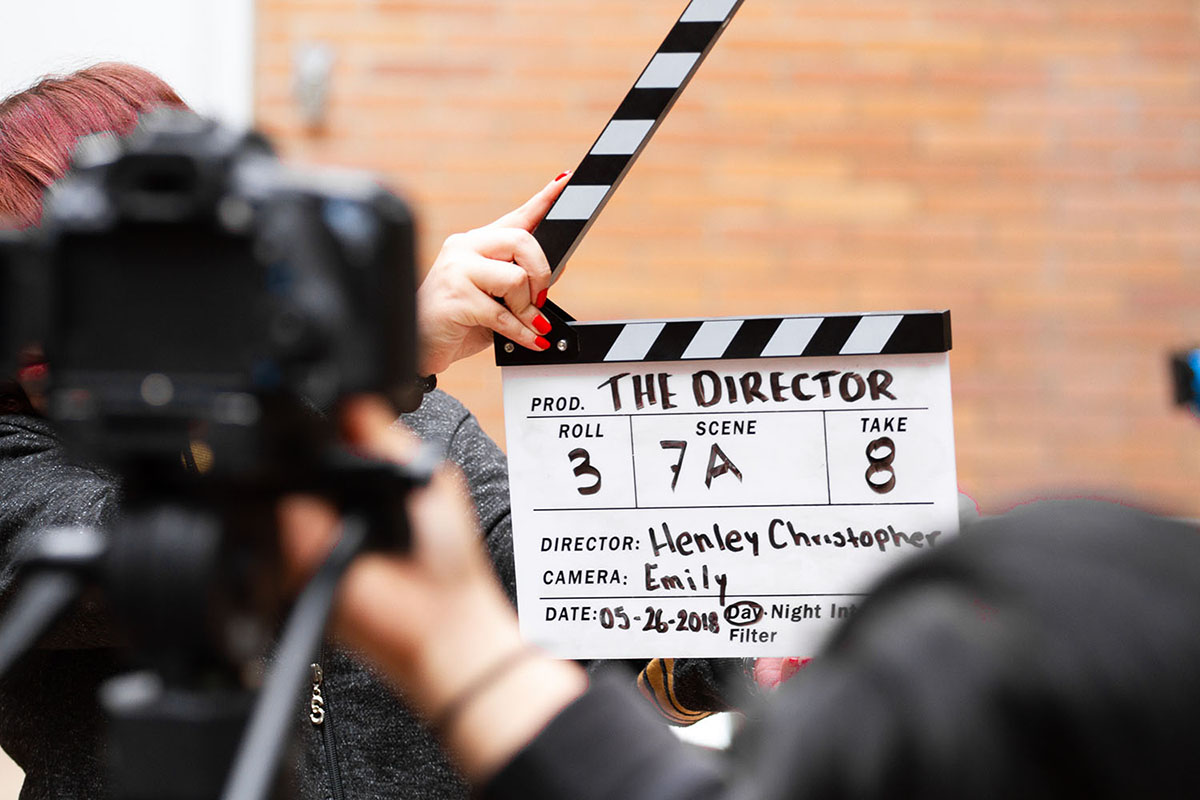 Une personne tient un clap de cinéma marqué 