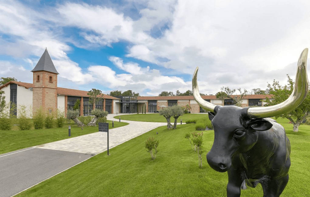 A Property Surrounded by Greenery With a Bull Statue in the Foreground. - Eventdrive Blog Article