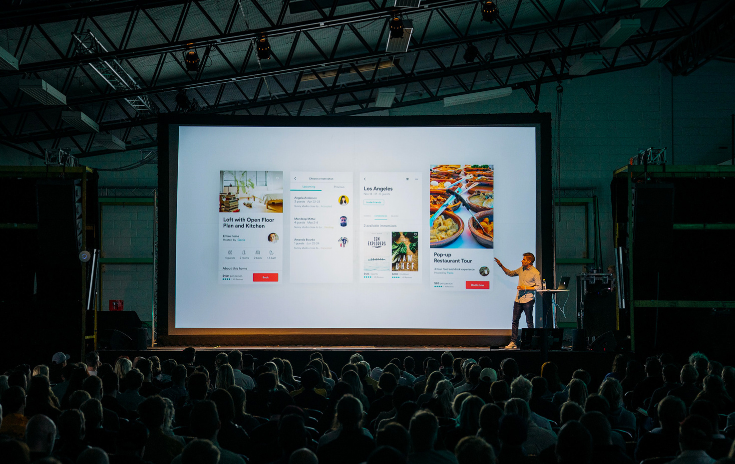 Un homme fait une présentation devant un large auditoire, debout face à l'écran de projection, tandis que le public écoute attentivement dans une salle de conférence. - Article de blog Eventdrive