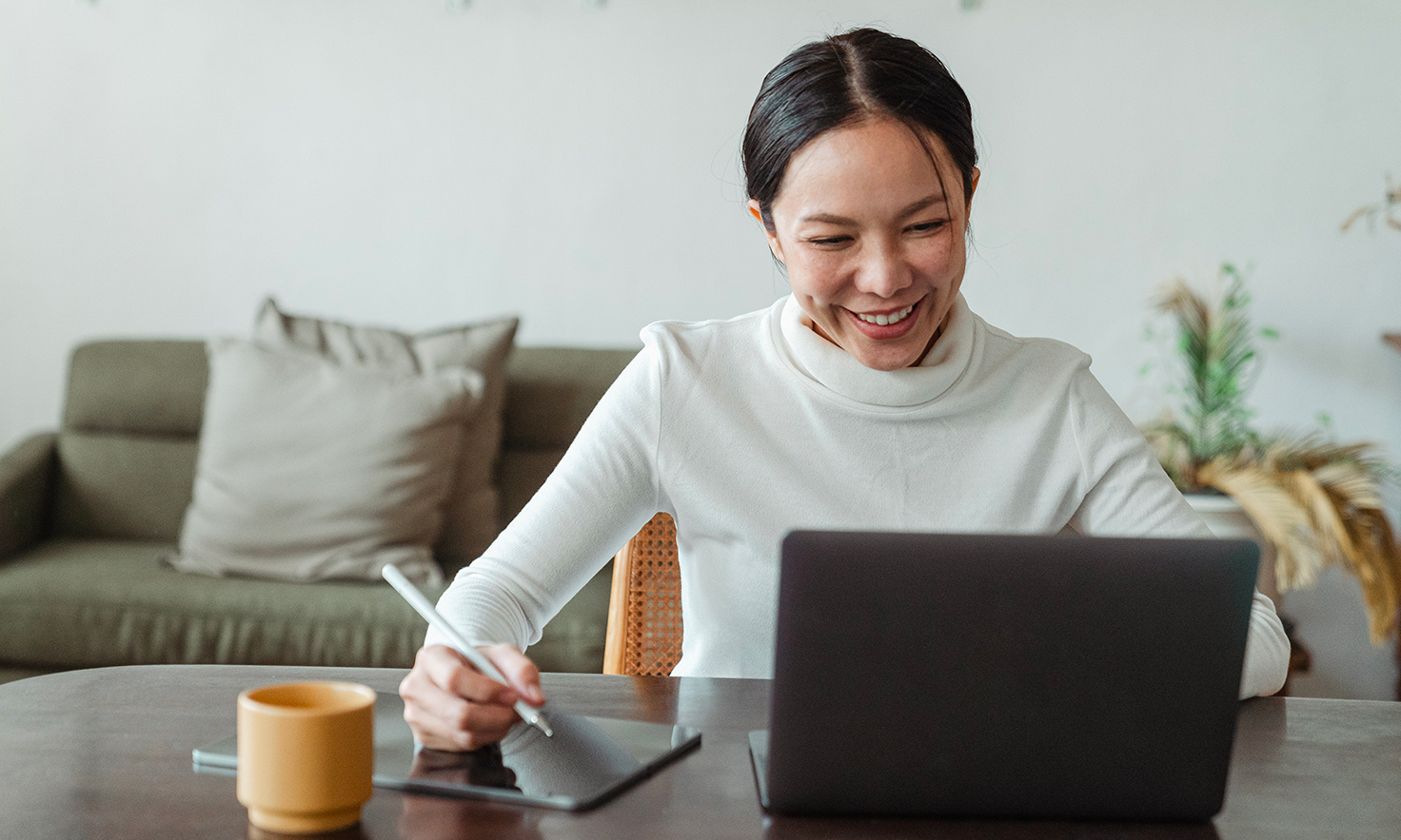 Une femme sourit, prend des notes en regardant son ordinateur portable - Article de blog Eventdrive