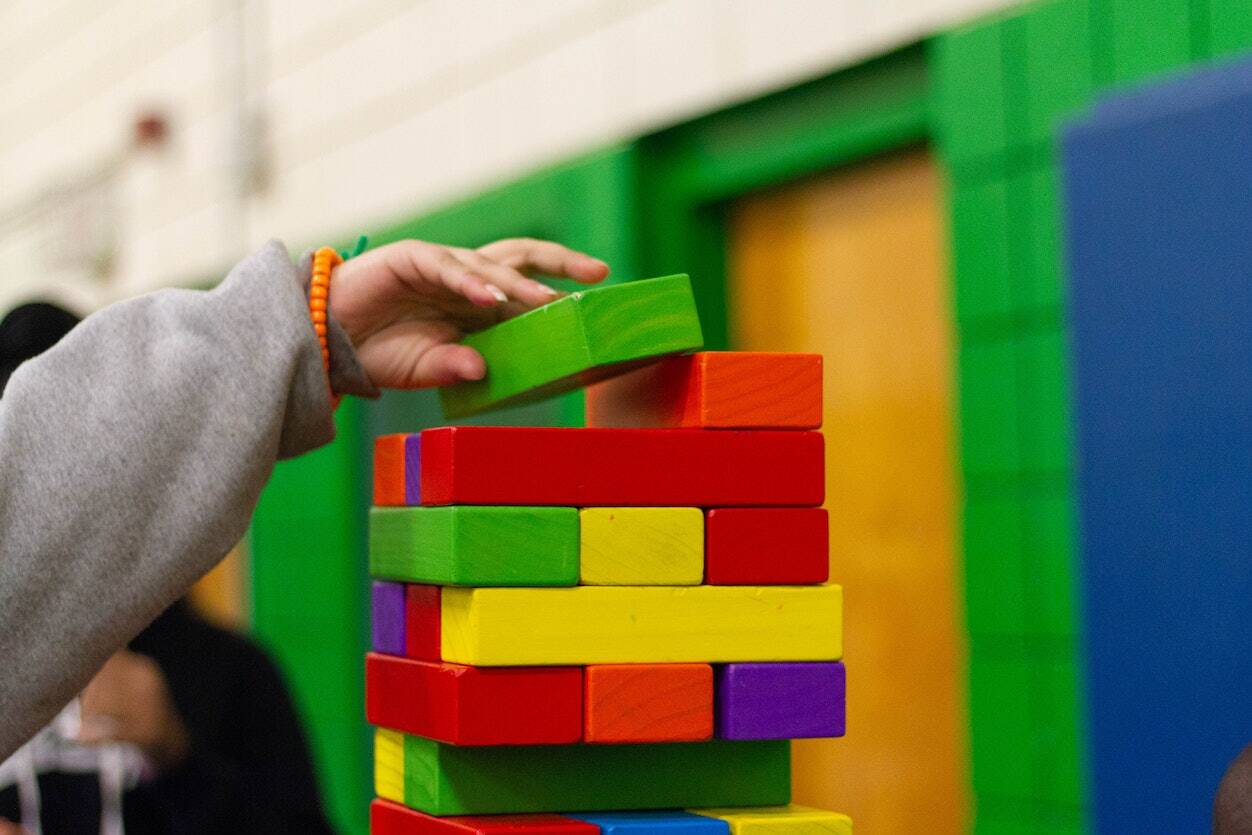 A Hand Stacking Colored Wooden Blocks in a Building Game. - Eventdrive Blog Article