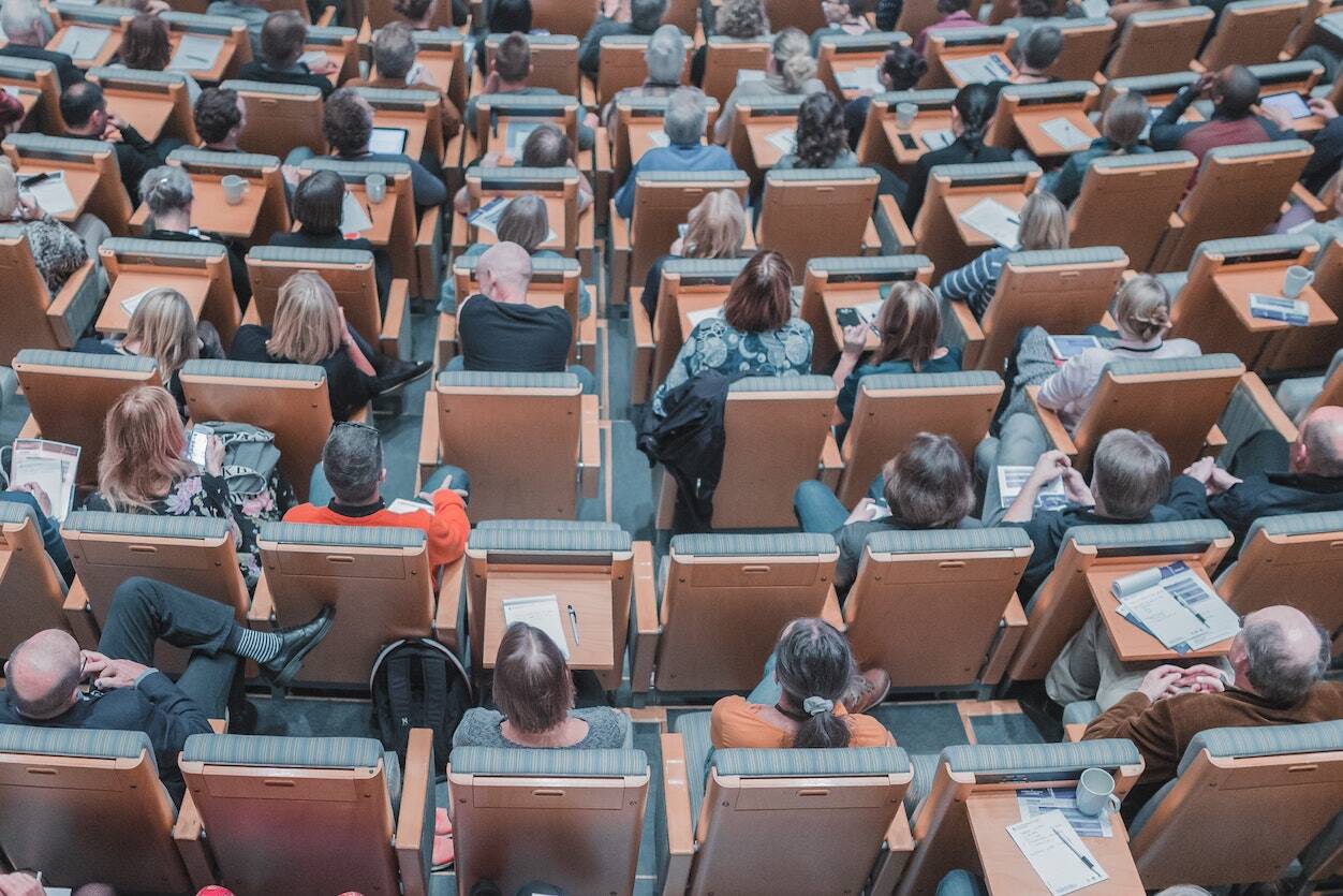 Un auditoire assis dans une grande salle assiste à une conférence, attentif à la présentation en cours. - Article de blog Eventdrive