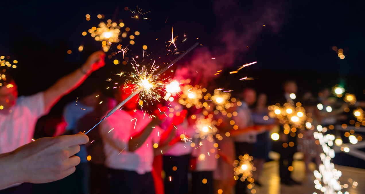 A group of people holds lit candles during a celebration. The sparks illuminate the darkness. - Eventdrive blog article