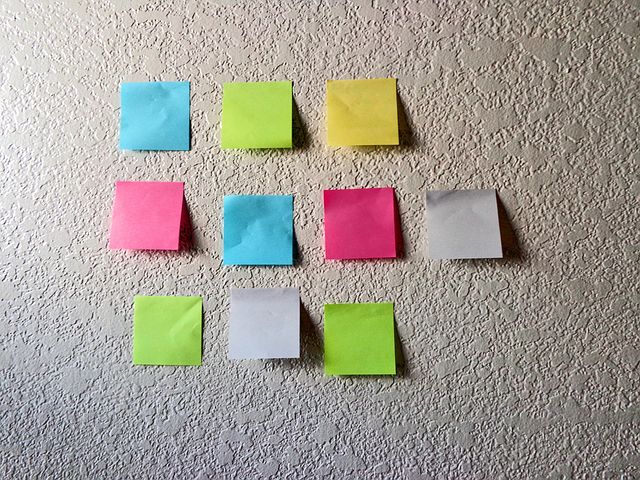 Neuf post-it colorés (jaunes, verts, roses, bleus et blancs) sont collés sur un mur texturé, disposés en trois rangées de trois. - Article de blog Eventdrive