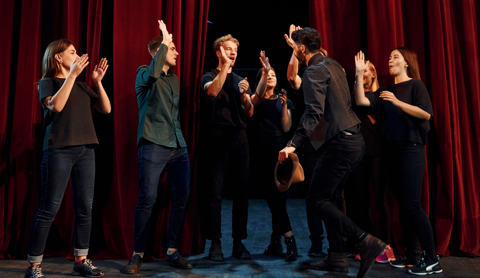 Un groupe de personnes dans un théâtre se tapent dans les mains.