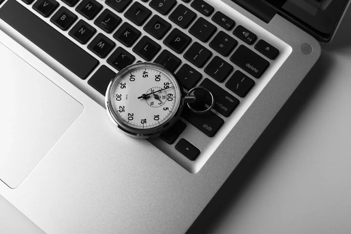 An analog stopwatch placed on a laptop keyboard. - Eventdrive Blog Article